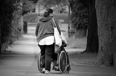 caregiver pushing a person in a wheelchair
