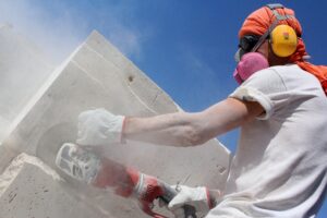 man grinding a stone slab with a respirator on