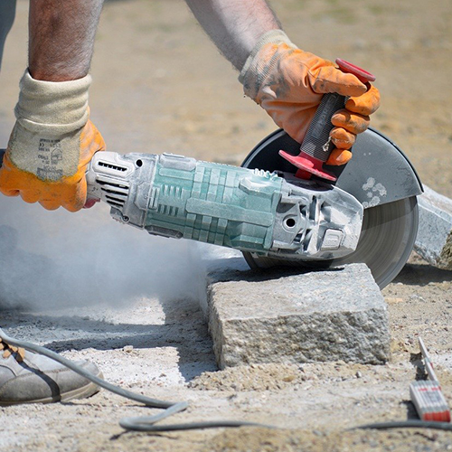 Person cutting toxic artificial stone slab being covered in toxic dust